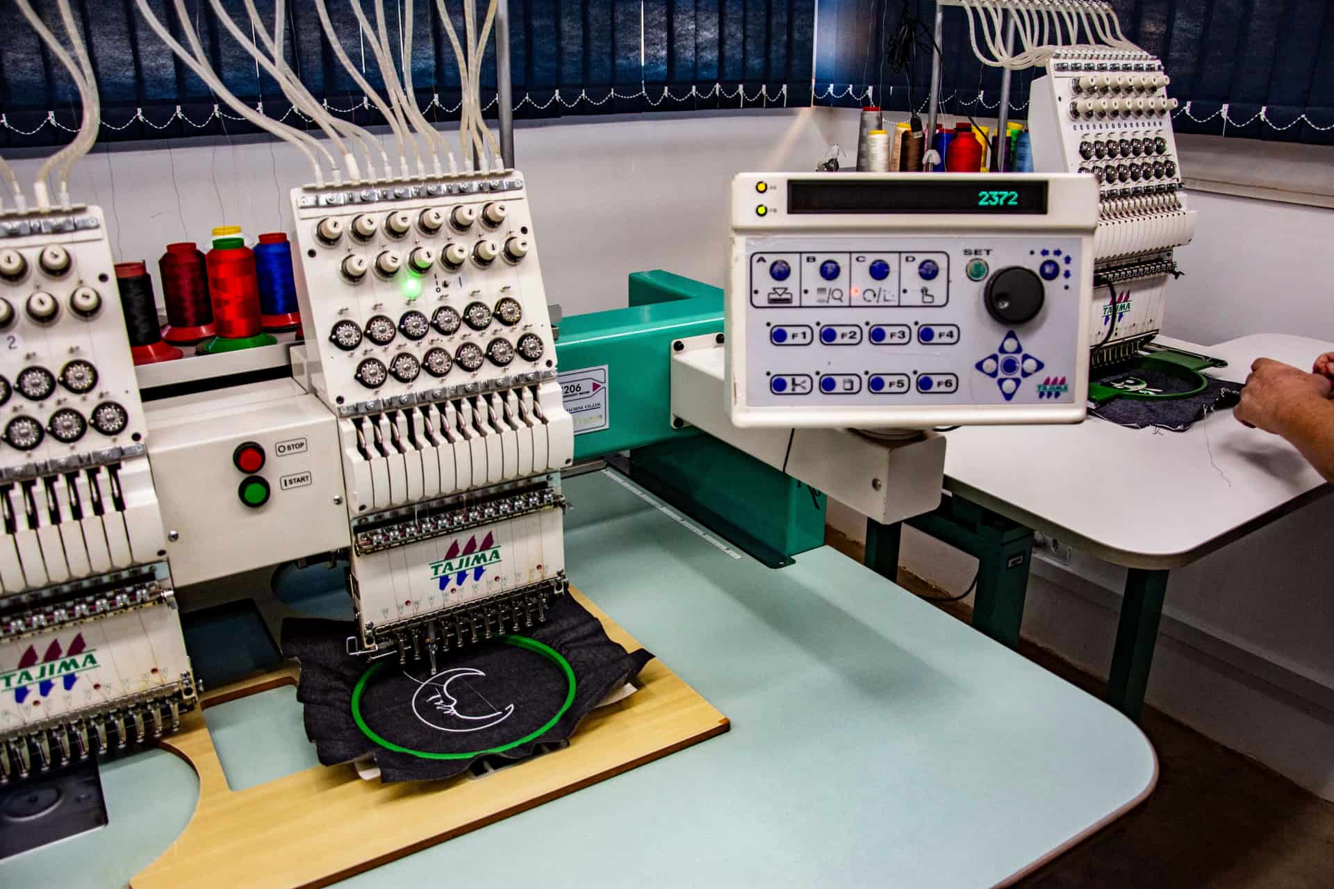 Embroidery machines lined up in a textile workshop - a stand-in for the Brother NQ1600E, not a photograph of this model
