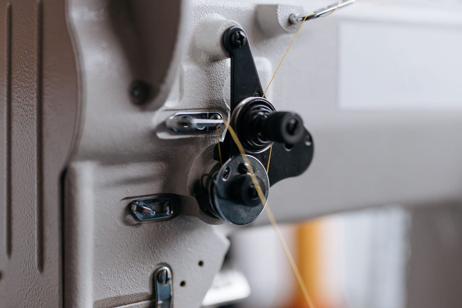 A detail of an industrial sewing machine's thread path and tension lever - a stand-in for the Handi Quilter Amara 20, not a photograph of this model