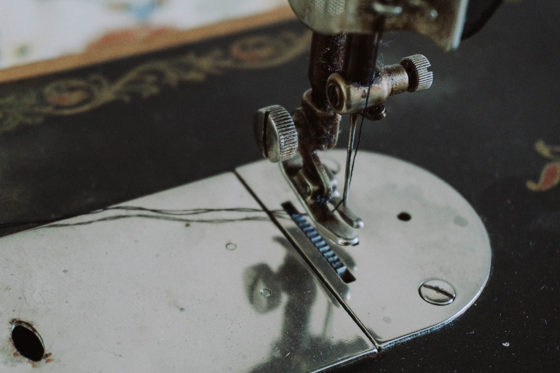 Close crop of a sewing machine needle, presser foot and thread