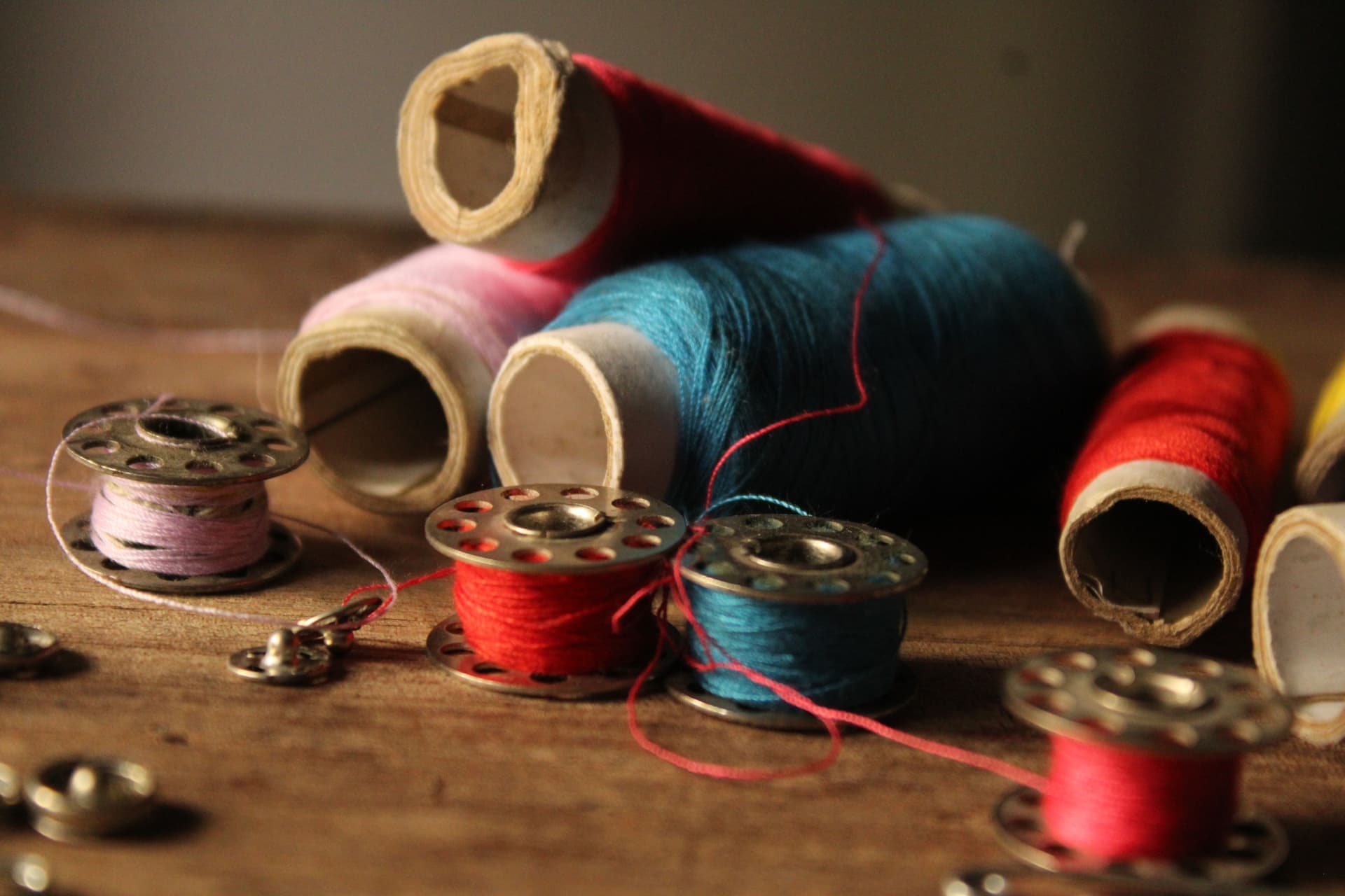 Spools of colored thread and bobbins laid out on a wooden table