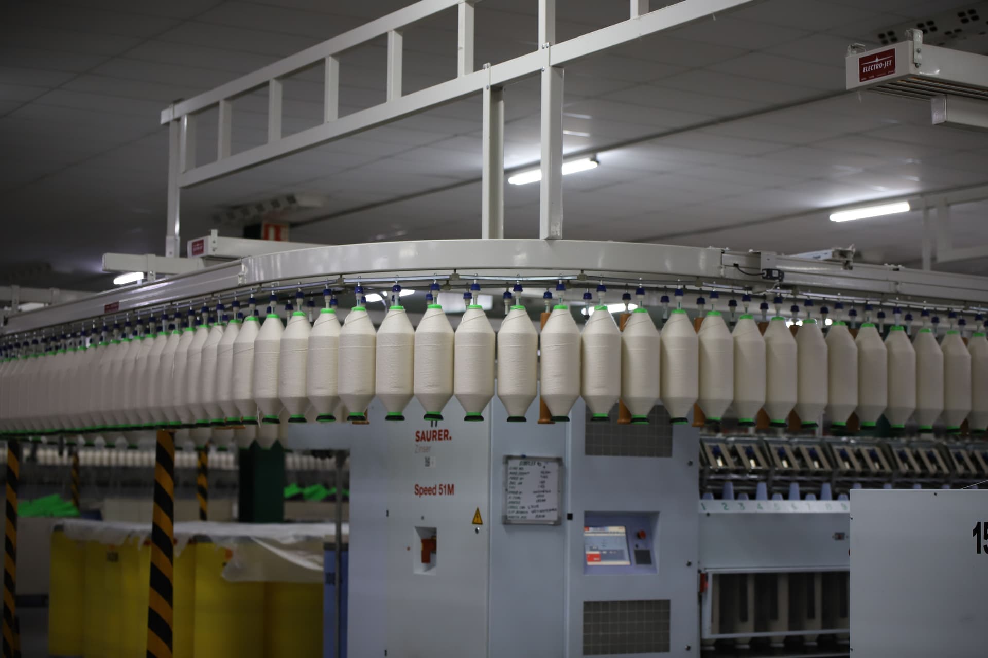 Rows of white thread feeding through a textile factory machine