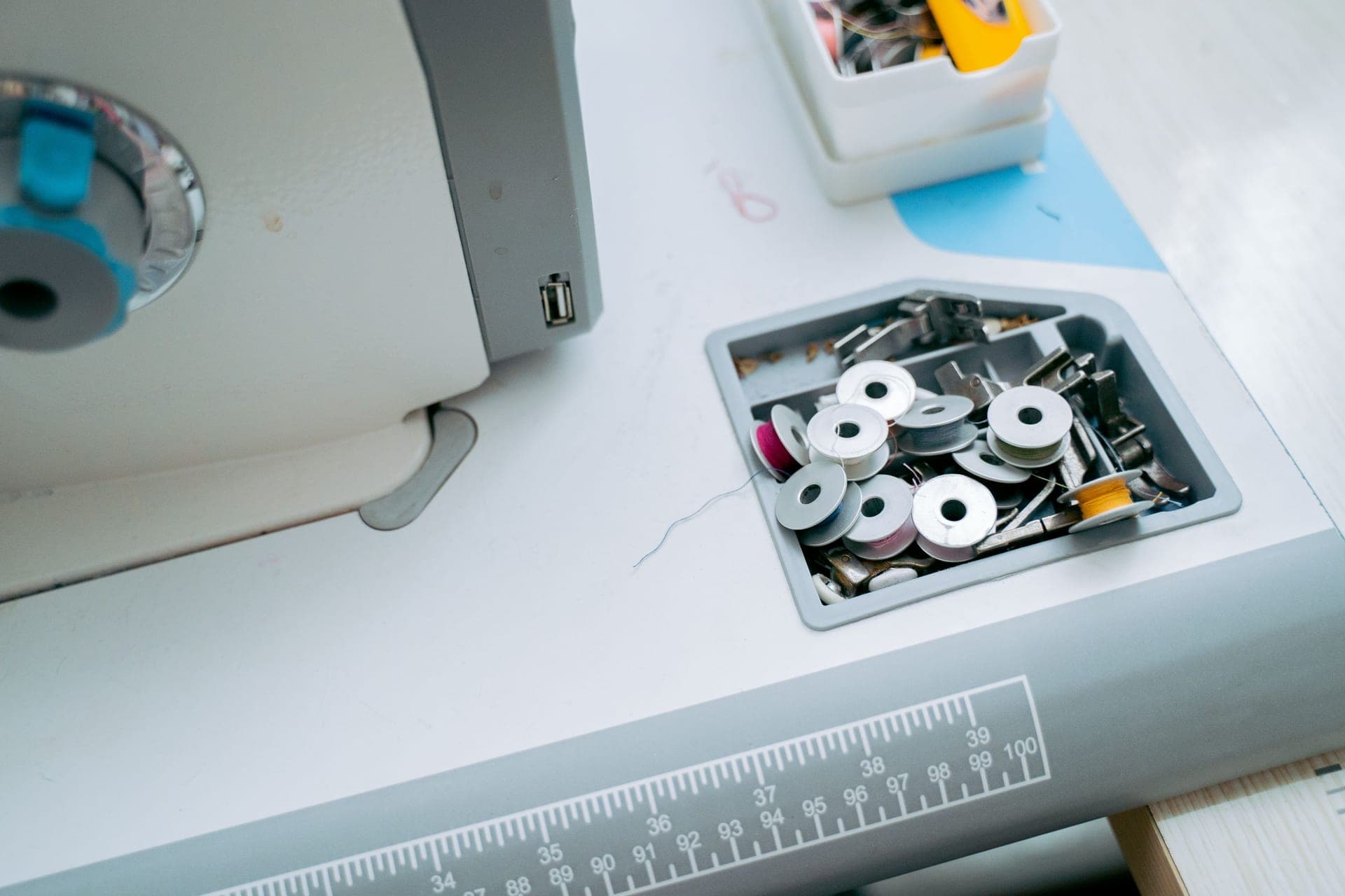 A workshop bench with a sewing machine, thread and tools laid out