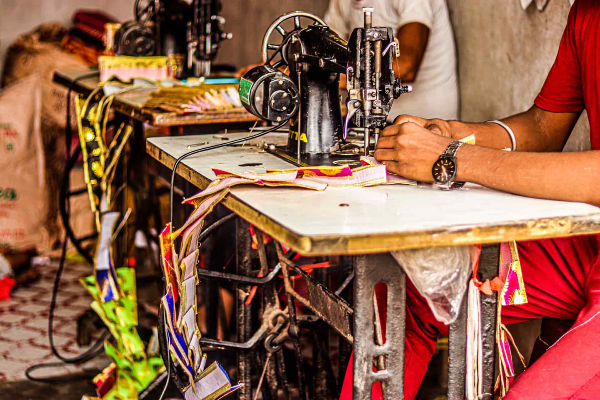 A tailor feeding colorful fabric through an industrial sewing machine